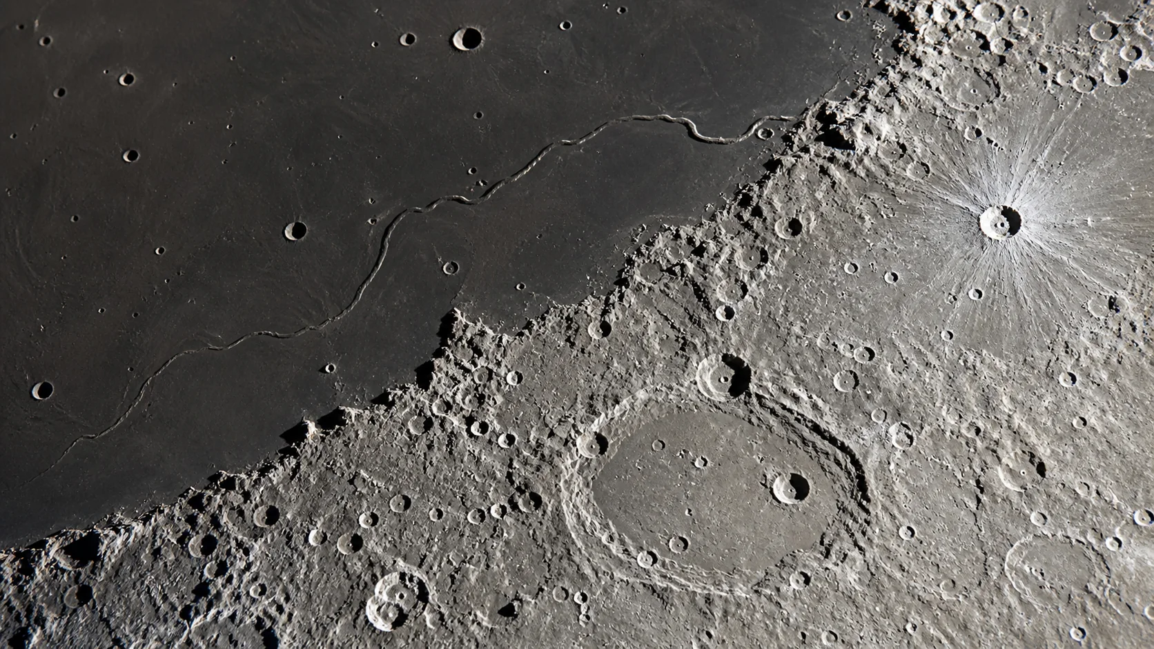 Frontière entre une mer lunaire sombre, des hauts plateaux clairs et une vallée sinueuse