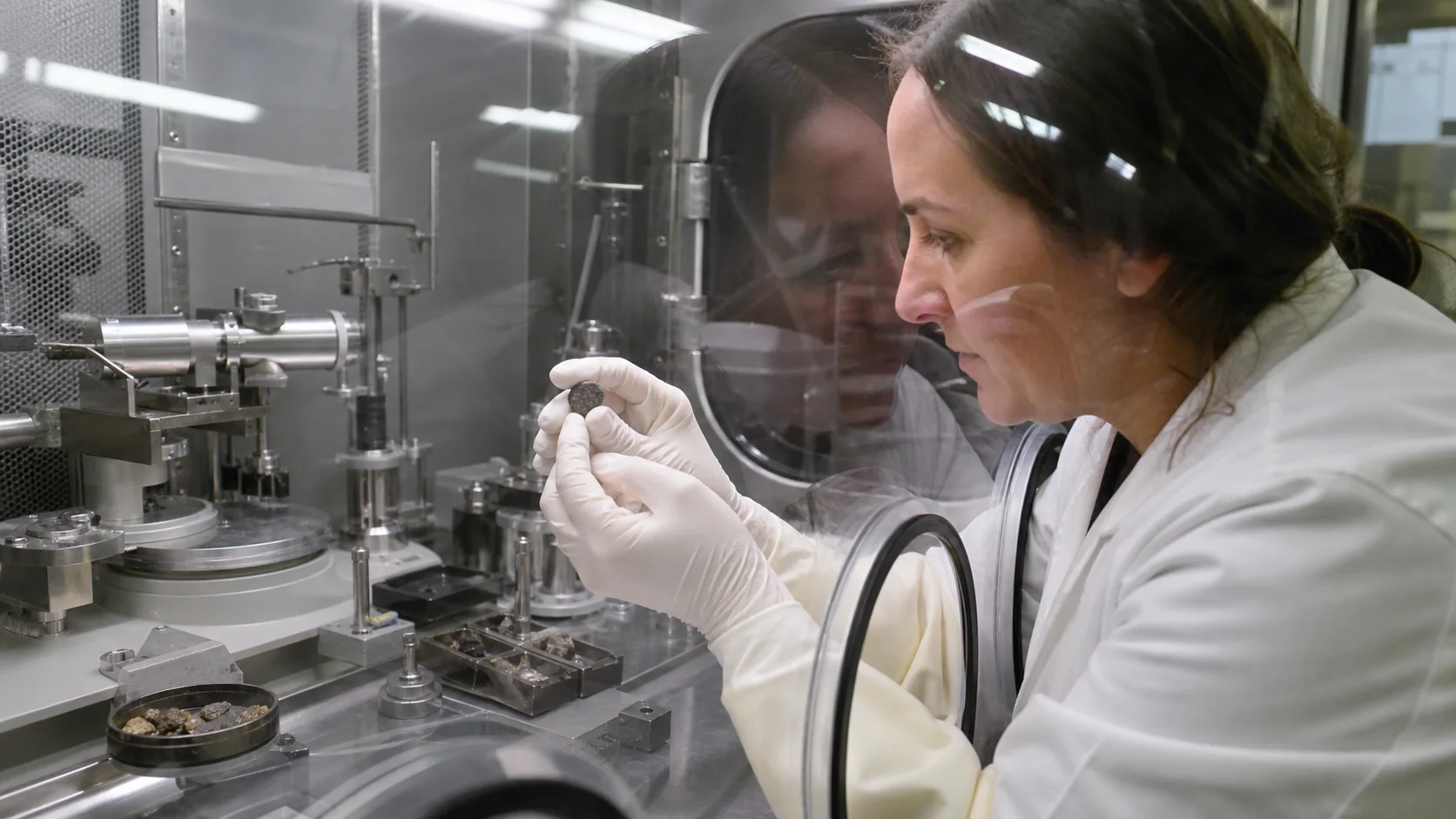 Scientifique examinant un échantillon lunaire dans une enceinte de laboratoire