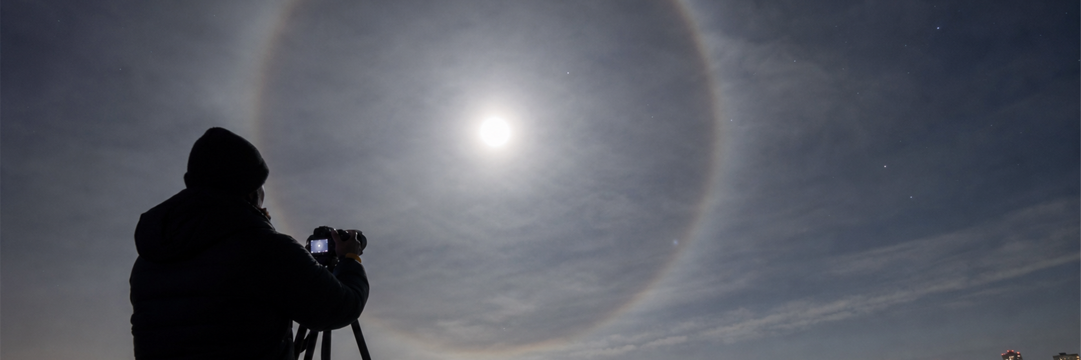 Observateur photographiant un halo lunaire au-dessus de la ville